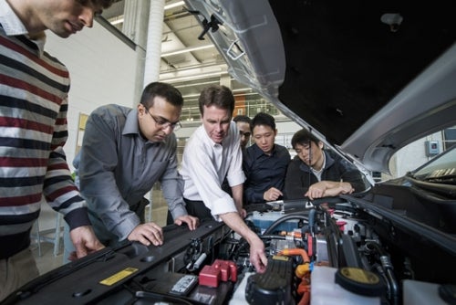 John McPhee and research assistants inspect a car engine.