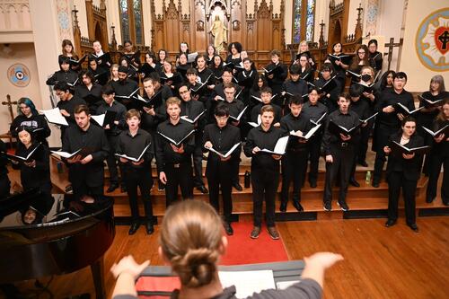 The University Choir, dressed in black, sings in a church sanctuary.
