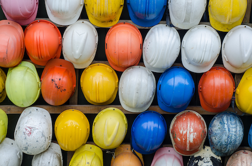 A collection of coloured hard hats hanging on a wall.