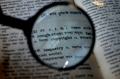A magnifying glass showing a close-up of the word &quot;copyright&quot; on a page.