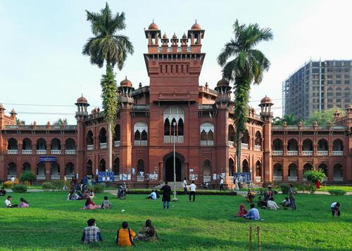 People sit on the lawn in front of Curzon Hall at the University of Dhaka.