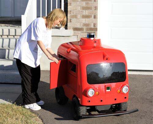A woman opens the door of the delivery bot.