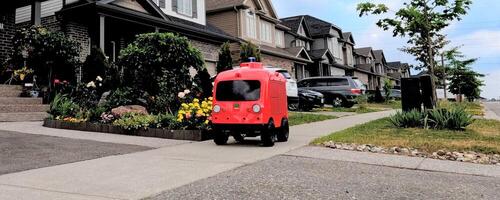 The LoopX robot drives along the sidewalk in a suburban neighbourhood.