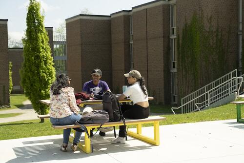 Students sit at a picnic table outside the Village 1 residence.