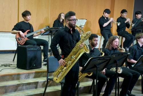 A baritone saxophone player stands to play a solo with the jazz ensemble.