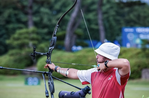 Olympian and Waterloo graduate Eric Peters takes aim with a bow and arrow.
