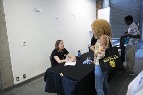 A new student is welcomed to campus by a volunteer.