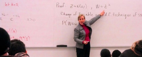 Cyntha Struthers delivers a lecture in front of a white board.