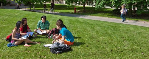 Students sit in a group on some campus green space.