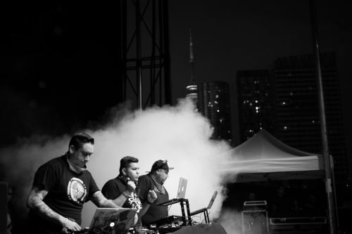 A Tribe Called Red performs with the CN Tower in the background.