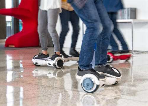 A group of people photographed from the waist down balancing on hoverboards.