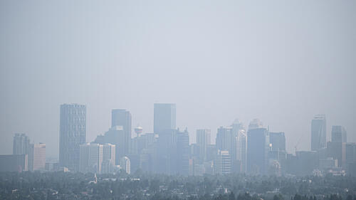 Smoke from forest fires blankets a city skyline.