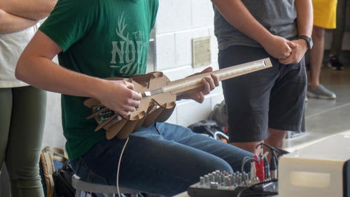 A student demonstrates their homemade electronic instrument.