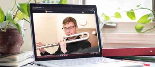 A laptop screen showing video of a man playing a flute.