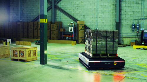 A robot moves a pallet on a factory floor.