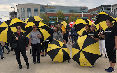 Volunteers hold University of Waterloo umbrellas in a crowd at the Waterloo Public Square.