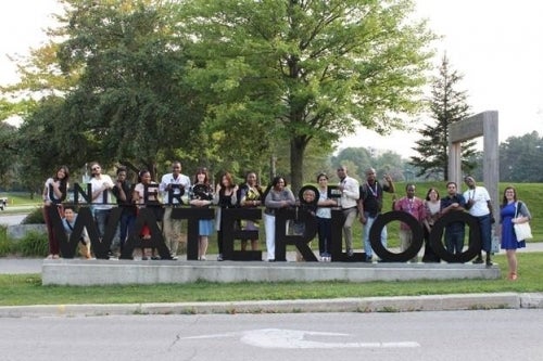 Students pose at the Waterloo entrance sign at University Avenue.