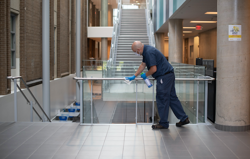A Plant Operations custodian cleans a balcony railing.