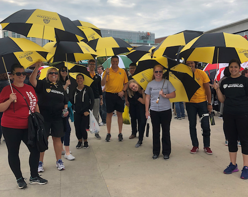 Waterloo volunteers holding UW-branded umbrellas.