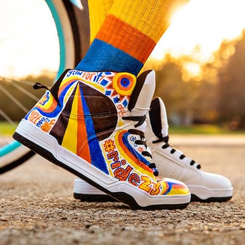 A person sports fancy high-top sneakers with the Ride for Refuge colours and logo on them.