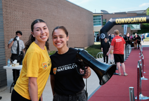 Two convocation ambassadors smile at the red carpet outside the PAC.