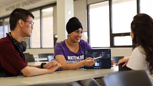 Three Engineering students discuss a display on a tablet.