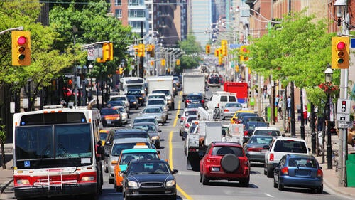 A busy urban Toronto street with buses, cars, bicycles and pedestrians