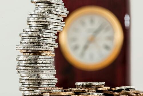 A stack of coins with a clock in the background.