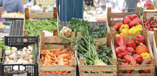 A stall at a farmer's market loaded with crates of vegetables.