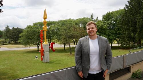 Brady Roberts stands near the 'pickle forks' sculpture outside the PAS building.
