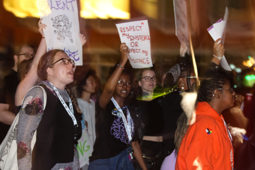 Women march while carrying protest signs.