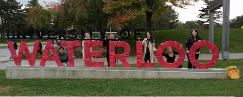 Volunteers stand before the University of Waterloo south entrance, which has been wrapped in red for the United Way Campaign.