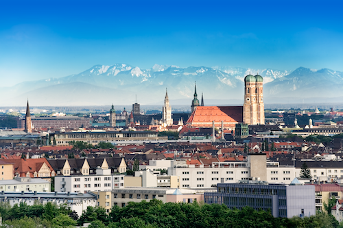 A panoramic view of Munich's old city with churches against the Alps in the distances.