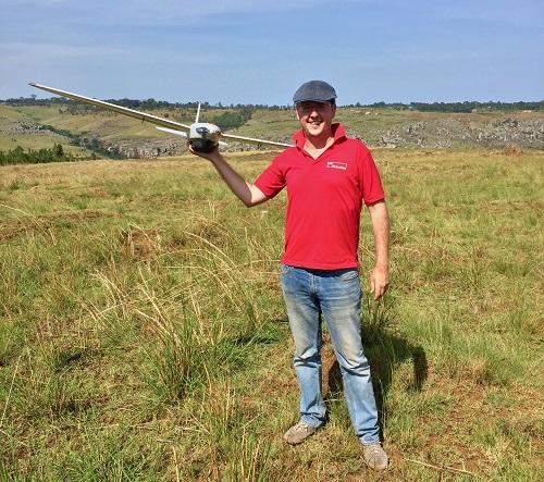 Patrick Meier holds a flying drone on a hillside in Tanzania.
