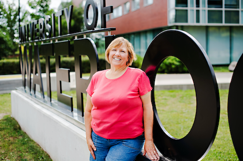 Sharon Lamont stands next to the University of Waterloo sign.