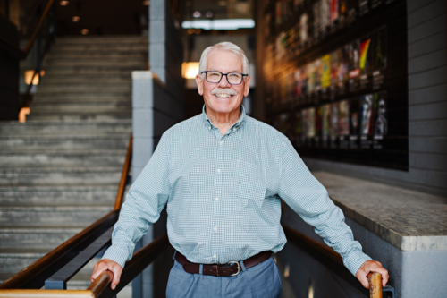 Maurice Dusseault smiles as he stands in front of a flight of stairs.