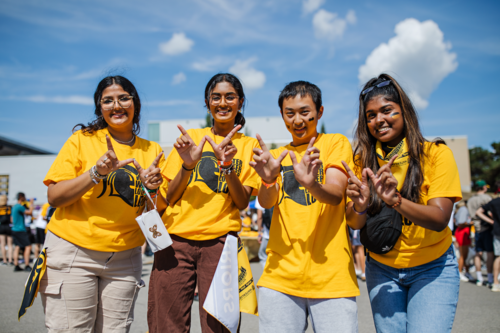 Students in UW t-shirts make a &quot;W&quot; sign with their hands.