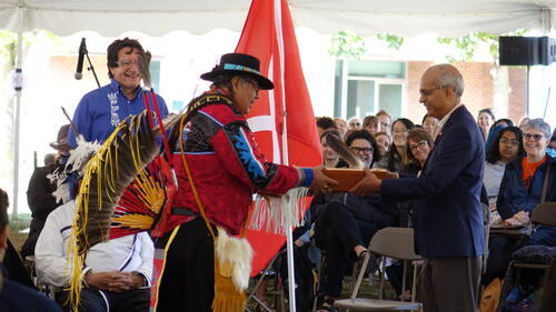 Vivek Goel, President and Vice-Chancellor of the University of Waterloo, receiving the gift of an eagle feather from Myeengun Henry, Indigenous Knowledge Keeper with Waterloo’s Faculty of Health.