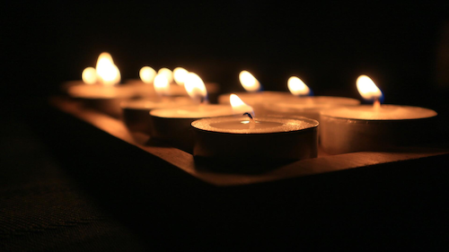 A number of candles lit in darkness.
