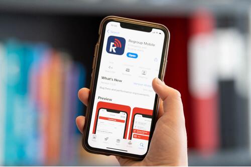 A person holds up a smartphone with the Regroup Mobile app on it.