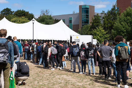 People line up outside a large tent for the Welcome Back lunch