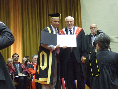 Dr. Delbert Russell stands on the convocation stage with Chancellor Prem Watsa as he receives his Distinguished Professor Emeritus status.