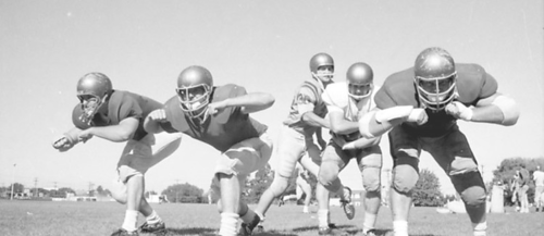 A black and white photo of university football players circa the late 1960s