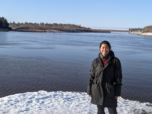 Celine Huab stands in front of a lake in Moose Factory.
