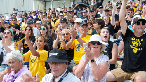 A crowd of Warriors supporters cheer the team on in the stands at Homecoming.