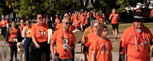 Vivek Goel, Jean Becker, and Myeengun Henry are among the people wearing orange shirts as they walk around ring road.