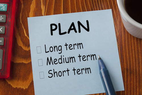 A piece of paper and a pen with a list that says &quot;Plan, Long term, medium term, short term&quot; with checkboxes.