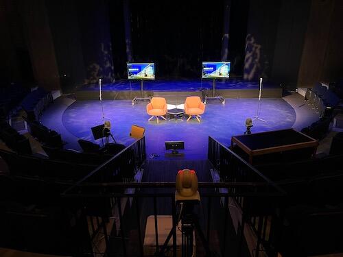 The stage setup for a previous town hall forum - two chairs on stage.