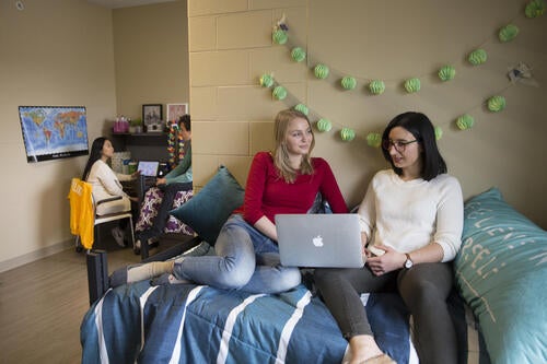 Two residents sitting on a bed in Claudette Millar Hall.