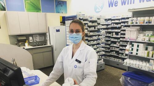 A School of Pharmacy student smiles as she works in a pharmacy setting.